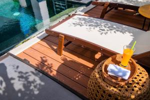 un bicchiere di succo d'arancia seduto su una panchina accanto alla piscina di Hoi An Majestic Villa a Hoi An