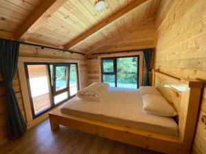 a bed in a log cabin with windows at Ayder Villa Gencal King in Ayder Yaylasi