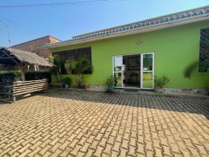 a green building with a brick courtyard in front of it at Suba Motel in Kihihi