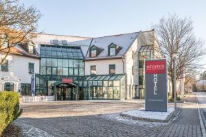 a building with a sign in the middle of a street at Atomis Hotel Munich Airport by Mercure in Oberding