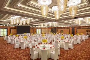 une salle de banquet avec des tables blanches, des chaises et des lustres dans l'établissement Crowne Plaza Tianjin Binhai Center, an IHG Hotel, à Binhai