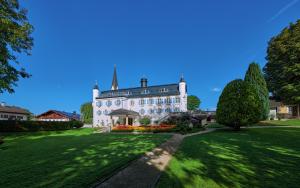 a large white house with a green lawn at Ferienwohnungen im Bonnschloessl in Bernau am Chiemsee