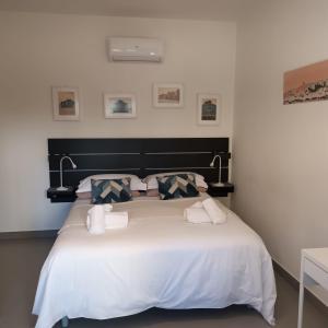 een slaapkamer met een groot bed met witte lakens en kussens bij A Casa Nostra B&B in Cagliari