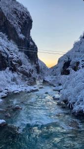 a river with snow on the side of a mountain at Guesthouse Gezim Selimaj in Valbonë
