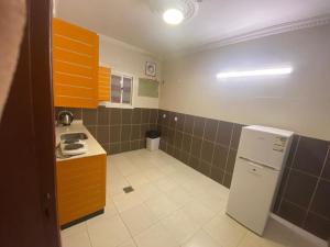 a small kitchen with orange cabinets and a white refrigerator at نون للشقق المفروشة in Jazan