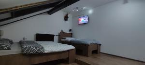 a bedroom with two beds and a tv on the wall at Mokusnice in Zenica