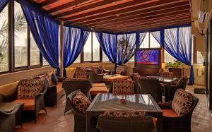 Mercure Grand Hotel Seef - All Suites في المنامة: مطعم والستائر الزرقاء والطاولات والكراسي