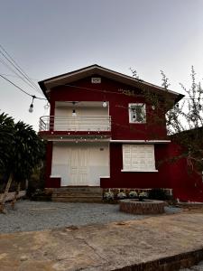 a red house with white doors and a driveway at Garden Homestay in Di Linh