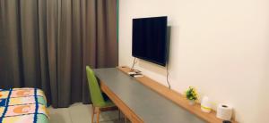 Zimmer mit einem Schreibtisch und einem TV an der Wand in der Unterkunft Kozi Square with Infinity Pool II in Kuching