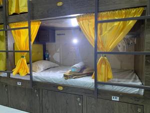 2 łóżka piętrowe z żółtymi zasłonami w pokoju w obiekcie Neenava Dormitory Asalpha w Bombaju