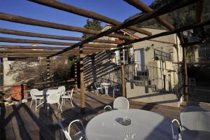 un patio con mesas blancas y sillas en una terraza de madera en Agriturismo La Contessa, en Finale Ligure