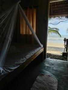 een bed in een kamer met uitzicht op het strand bij Bucana Beach Camp in El Nido