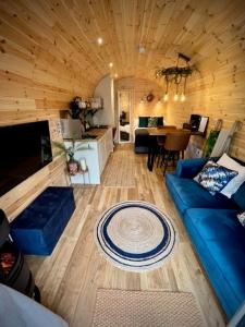 New Farm Cheshire Holidays في وينسفورد: غرفة معيشة مع أريكة زرقاء ومطبخ