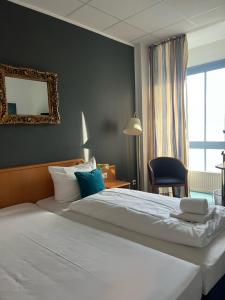 1 dormitorio con 1 cama blanca grande y 1 silla en Stargaze Forum Hotel Düsseldorf-Hilden, en Hilden