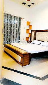 a bedroom with a large bed with a wooden frame at QueensLand villa near Islamabad airport & motorway in Rawalpindi