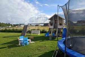 a backyard with a playground with a house and a trampoline at Comfortable premium class apartment shared swimming pool Gaski in Gąski