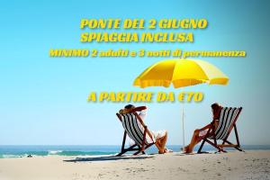 dos personas sentadas en sillas bajo una sombrilla en la playa en Hotel Riposo, en Gatteo a Mare