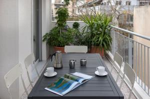 アテネにあるLeonidas Loft in the heart of Athens by GHHのバルコニー(黒いテーブル、コーヒーカップ、新聞付)