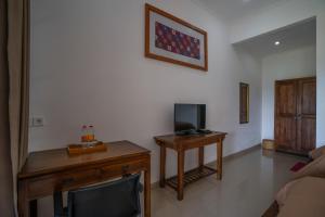 a living room with a tv and a desk with a television at Wiras Village in Canggu