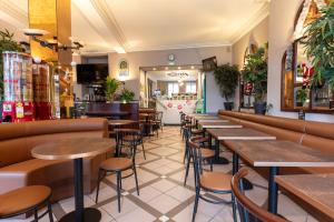 un restaurant avec des rangées de tables et de tabourets dans l'établissement Hôtel Café les Fleurs, à Argelès-Gazost