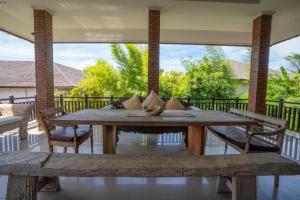 een houten tafel en banken op een veranda met uitzicht bij Wiras Village in Canggu