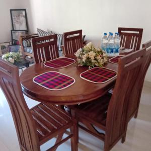 - une table à manger en bois avec 4 chaises et des bouteilles d'eau dans l'établissement Zuni`s Home Stay, à Kandy