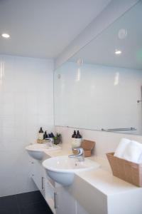 Baño blanco con 3 lavabos y espejo en Sea View Guest House, en Hobart