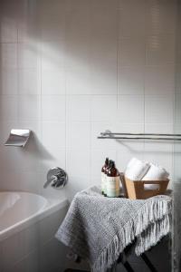 un baño blanco con bañera y una mesa con toallas. en Sea View Guest House en Hobart