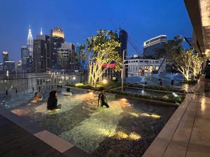 uma piscina com pessoas nela com um horizonte da cidade ao fundo em AXON RESIDENCE KLCC BY JD em Kuala Lumpur
