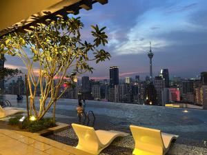 uma piscina no último piso com cadeiras e um horizonte da cidade em AXON RESIDENCE KLCC BY JD em Kuala Lumpur