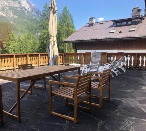 una mesa de madera con sillas y una sombrilla en el patio en Holidays on Dolomites, en Villanova