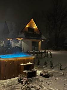 ein Haus im Schnee in der Nacht in der Unterkunft Osada Zbójnicka Turnia in Kościelisko