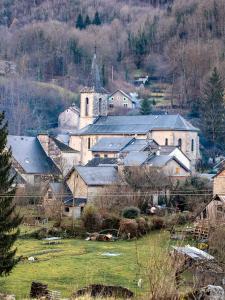 a group of buildings with a church and a field at Bergerie Ariégeoise in Ustou