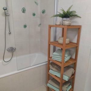 La salle de bains est pourvue d'une étagère en bambou, de serviettes et d'une baignoire. dans l'établissement FeWo Hope, à Lindwedel