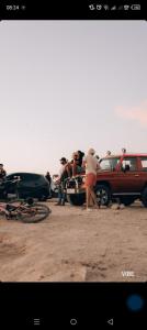 a group of people standing next to a red truck at Atlas surf in Tamraght Ouzdar