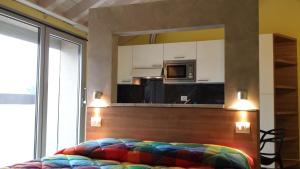 a colorful bed in a room with a kitchen at Residence Luna di Monza in Monza