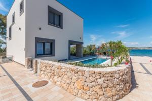 a house with a stone wall and a swimming pool at Royal House 1 in Pašman