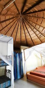 Cette chambre comprend un lit et un plafond en bois. dans l'établissement Le Chamama, à Niaga