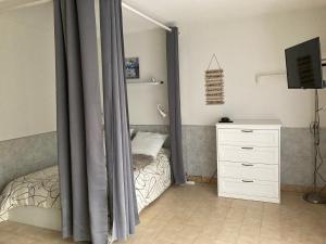 a bedroom with a bed and a dresser and a television at Le Beaulieu appartement T1 Bis RDC classé 3 étoiles avec parking à Barbotan in Cazaubon