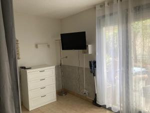 a bedroom with a television and a dresser with a window at Le Beaulieu appartement T1 Bis RDC classé 3 étoiles avec parking à Barbotan in Cazaubon