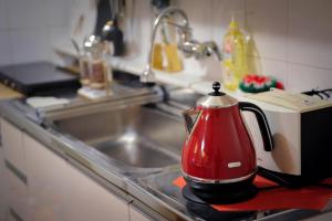 a red tea kettle sitting on a counter next to a sink at QQQ 3room spacious house at Jamsil in Seoul