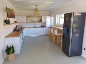 a kitchen with white cabinets and a black refrigerator at Versveld Cottage in Yzerfontein