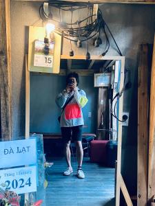 una mujer tomando una foto de sí misma en un espejo en Hostel-John Cafe and Beer en Da Lat