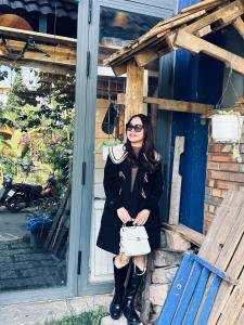 a woman wearing a black coat and black boots at Hostel-John Cafe and Beer in Da Lat