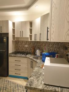 een keuken met witte kasten en een zwarte koelkast bij Sharm Hills in Sharm El Sheikh