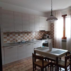 una cocina con armarios blancos y una mesa con sillas. en Casa Gabriel, en Toscolano Maderno