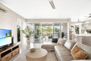 a living room with a couch and a tv at The Anchorage - Ultimate Waterfront Villa in Yorkeys Knob