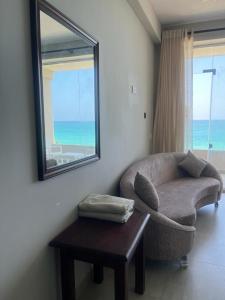 een woonkamer met een stoel, een tafel en een spiegel bij Blue Wave Beach Villa by Aaryan Group in Ambalangoda