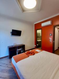 a bedroom with a large bed and a television at Rainbow Hotel Depandance Joli in San Marino