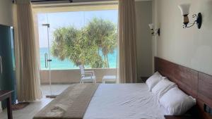een slaapkamer met een bed en uitzicht op de oceaan bij Blue Wave Beach Villa by Aaryan Group in Ambalangoda
